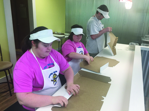 LifeSteps participants Megan Goldinger, Alicia Maycock and Michael Anderson fold boxes while working at the Funky Monkey.