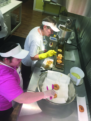 Donut maker Marge Check keeps a constant watch on the donuts while they are frying while granddaughter Megan Goldinger prepares the donuts for customization.